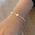Close-up of beaded bracelet with white pearls and gold letter K charm on a wrist - Letter K Style (K)
