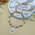 Close-up of a woven multicolor bracelet with silver metal rings and a central relief pendant - Colored Rope Silver Spacers Bracelet: Zaki Lhamo