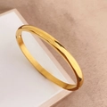 Dettaglio ravvicinato di un bracciale rigido in acciaio al titanio dorato lucido e spazzolato - Oro