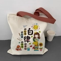 Detail of canvas tote bag featuring motivational slogans and brown shoulder straps - Self-Discipline Beige