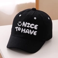 Close-up of white 3D embroidery showing NICE TO HAVE and smiley face on black baseball cap - 52cm (2-5 Years) / Black