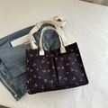 Black tote bag with red cherry print, dual front pockets and adjustable shoulder strap - Black
