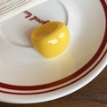 Detail of yellow oval resin ring with glossy candy texture on white ceramic plate - Yellow