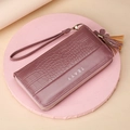 Long purple crocodile texture wallet with wrist strap and tassel on pink pedestal - Purple
