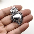 Vue macro d'un pendentif cœur gothique argenté avec motifs de flammes sur fond blanc - Argenté