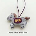 Dettaglio del ciondolo cavallo in peluche grigio con sella viola e ricamo dorato portafortuna - Stile Cinturino / Grigio (Buona Fortuna)