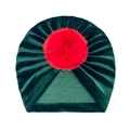 Detail of baby velvet turban hat in dark green with a large red faux fur pom-pom - One Size / Dark Green + Red