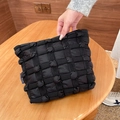 Detailed close-up of a black puffy cloud quilted texture makeup bag with side logo tag - Black