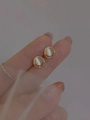 Macro shot of gold circular earrings featuring white cat eye stones in a minimalist design - Opal Small Studs / Gold
