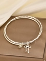 Détail du bracelet argenté à double couche avec breloques noeud et coeur sur du satin - Bracelet Jonc Pendentif Coeur Argent / Argent