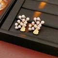 Detalle de pendientes vintage de flores con perlas sobre una bandeja de cuero negro - Pendientes de Botón de Flor Dorada (Pin de Plata 925)