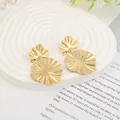 Dettaglio degli orecchini a cuore in metallo liquido dorato su un espositore in pietra bianca - Oro EH001 (Petalo Plissettato)