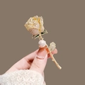 Elegant gold rose brooch with sparkling rhinestones and a pearl accent on a brown background - X0361 Gold Rose