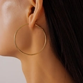 Close-up of a model wearing large golden geometric hoop earrings with polished finish - 5cm / Gold