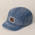 Détail d'une casquette en denim bleu vintage avec écusson marron et œillets en métal - Bleu foncé