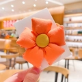 Handheld shot of an orange floral fabric hair tie for girls with a yellow center - Orange - Solid Color Flower