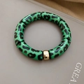 Detailed macro view of green leopard print resin tube beads with gold metal spacer bead - Bracelet-Green