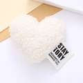 White plush heart accessory with fabric label on minimal white and brown paper background - White