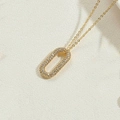 Gros plan d'un collier doré avec pendentif ovale serti de zircons blancs brillants - Or 14K Zircone Blanc