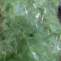 Close-up of bulk green iridescent resin fishtail charms with hanging loops in a bag - Luminous Glitter Fishtail Green