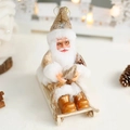 Papá Noel con túnica dorada en un trineo de madera con botas doradas brillantes de adorno - Trineo Dorado