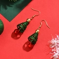 Détail de boucles d'oreilles sapin de Noël avec paillettes vertes et cloches rouges sur fond rouge - Vert/Rouge/Or