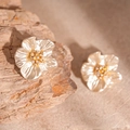 Makro-Detail von Acrylperlen-Blumenohrringen mit Goldbeschichtung und funkelnden Zirkon - Blumen Ohrstecker / Perlweiß