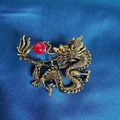 Detailansicht der Vintage-Gold-Drachenbrosche mit roter Perle auf blauem Seidenstoff - Rückkehrender Drache Mit Roter Perle