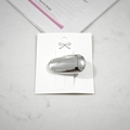 Dettaglio di un fermaglio per capelli ovale in metallo argentato su cartoncino - Forma di Fagiolo / Lucido / Ovale d'Argento