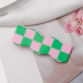 Detail der gewellten grün-rosa karierten Harz-Haarspange auf einem Blumenmustergrund - Rosa & Grün