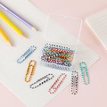 Colorful checkered paper clips in a clear plastic organizer box on a pink desk background - Zebra Pattern