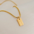 Macro shot of 18K gold plated square pendant with engraved letter I on a box chain - Letter I