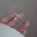Macro shot of minimalist s925 silver butterfly stud earring held on a fingertip - Hollow Butterfly / Silver