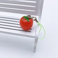 Red tomato pendant phone strap with green leaf and lanyard on a white bench - Tomato