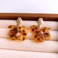 Macro-detail van amberkleurige acryl bloemblad oorbellen met gouden studs en luipaardprint - Zilveren oorbelpost - Koffie
