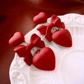 Matte red heart and bow dangle earrings with gold rings on white ceramic plate - Heart Bow Earrings