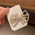 Elegant gold hair clip featuring white pearls in a bow design on a premium card holder - Multilayer Bow