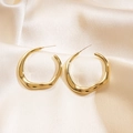 Irregular golden wavy round earrings on champagne silk satin background - Gold