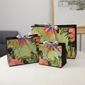 Three assorted sizes of floral paper gift bags with palm leaves and gold handles - S / Silver Ribbon
