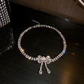 Macro shot of silver bow pendant with crystal tassels and sparkling rhinestone chain - Bowknot Necklace / Silver