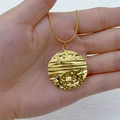 Golden hammer-textured round pendant necklace held in hand for size visualization - Round