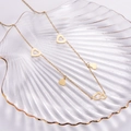 Minimalist gold titanium steel necklace with heart pendants in a glass shell dish - Gold