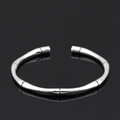 Detailweergave van een zilveren bamboe-stijl open armband op een zwart oppervlak - Stijl 3