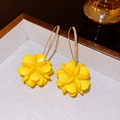 Gros plan de boucles d'oreilles fleurs jaunes avec strass brillants sur les crochets incurvés - Jaune