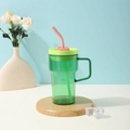 Detail of green transparent plastic cup with handle, green lid, and pink straw with ice - 20oz / Green