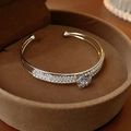Dettaglio del bracciale camelia in argento con zirconi in una scatola marrone - Bracciale Aperto Camelia / Argento