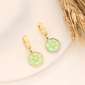 Close-up of gold daisy earrings with green petals and yellow stamens on a ceramic plate - Green