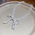 Detail of beaded pearl necklace with woven bow design on elegant cream ceramic plate - Necklace-White