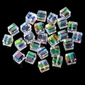 Macro detail of aurora AB cubic glass beads with faceted surfaces and central holes - Pink and Green