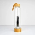 Detalle de la botella de agua de cristal con tapa de bambú y piedras negras naturales - Negro